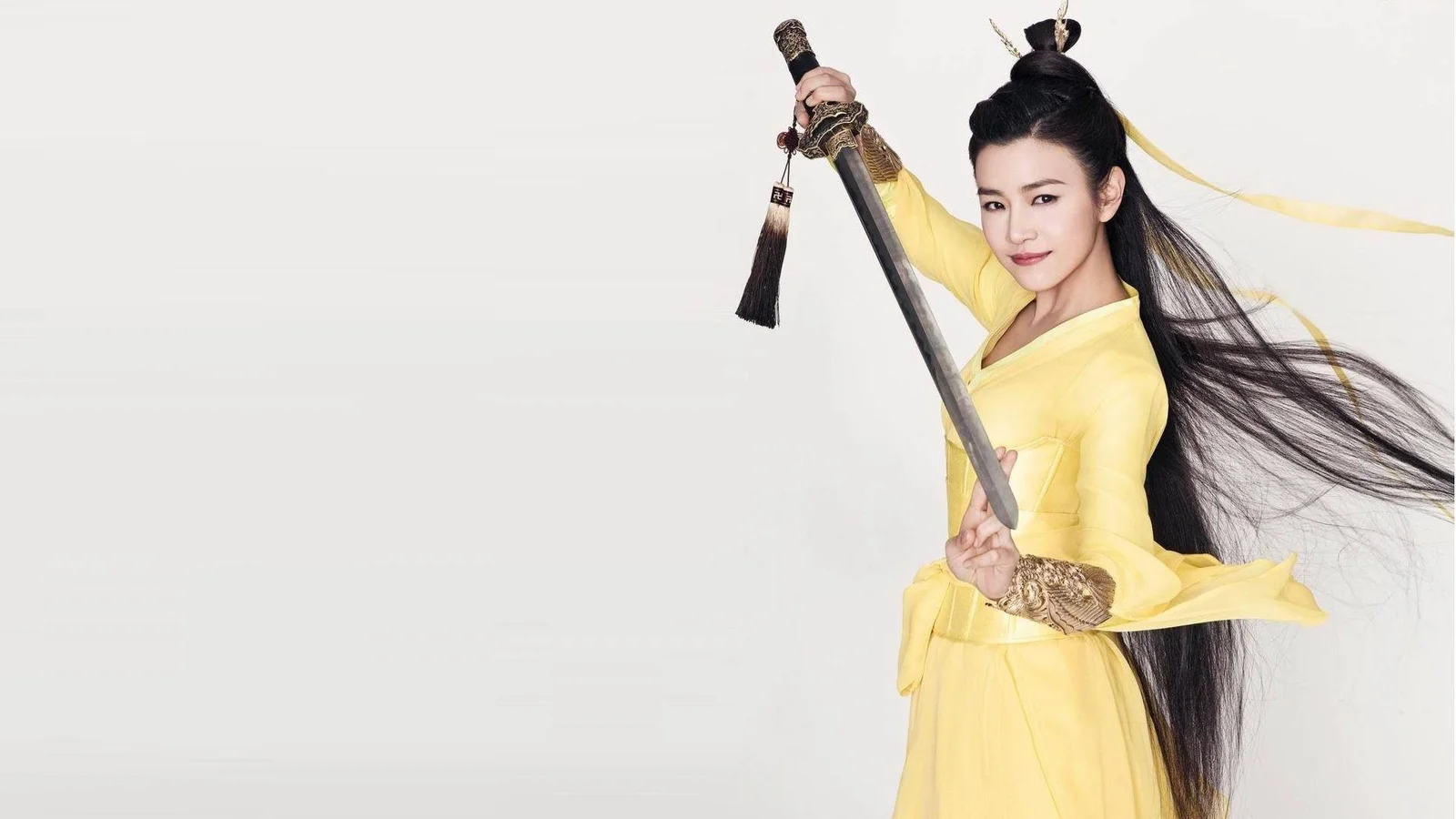 一名身穿黄色服装的成年女子在浅色背景前手持长剑。