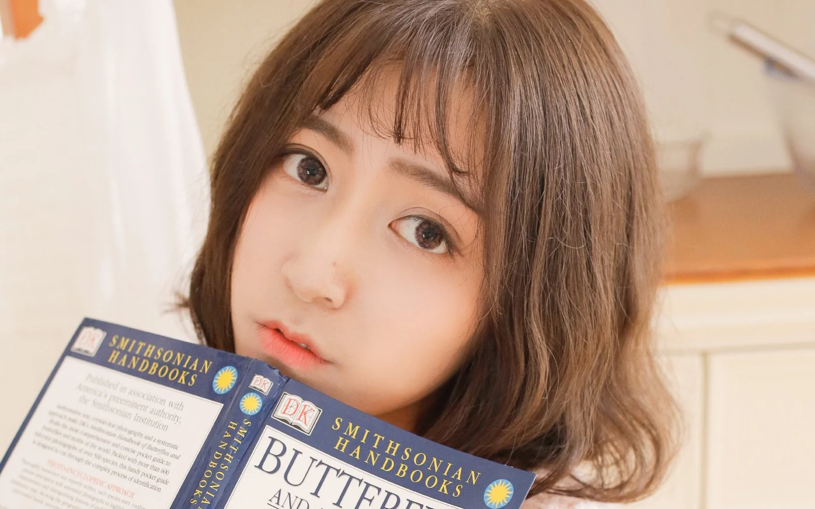 一名棕发女子手捧一本打开的书进行近距离自拍。