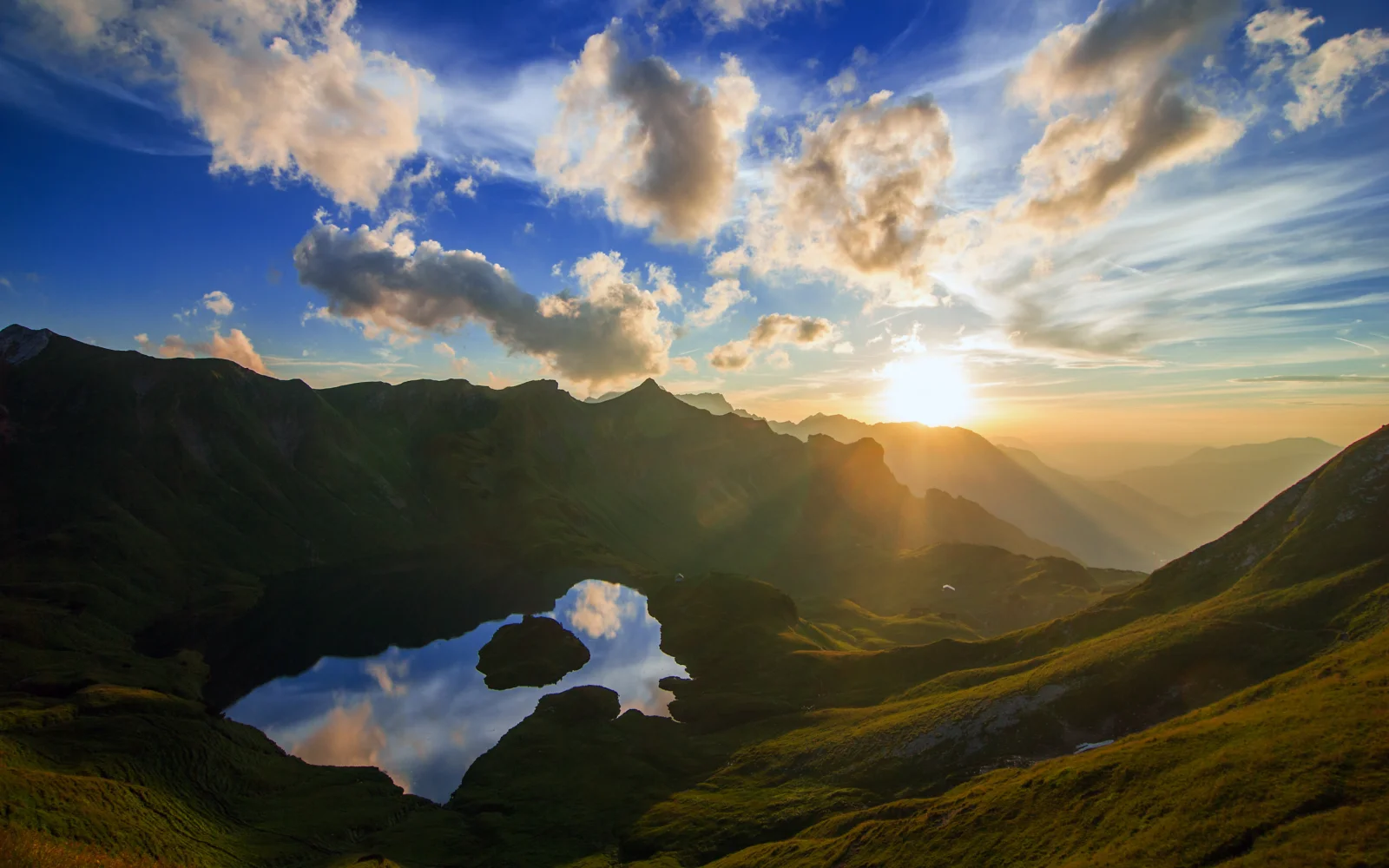 群山环抱的高山湖泊映照着夕阳与绚丽云层。