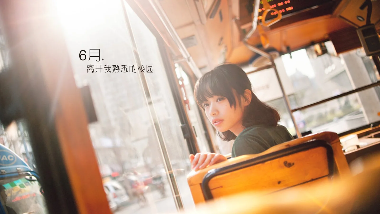 一名女子坐在车厢内靠近车窗的位置，温暖阳光照亮了她和周围的木质座椅。