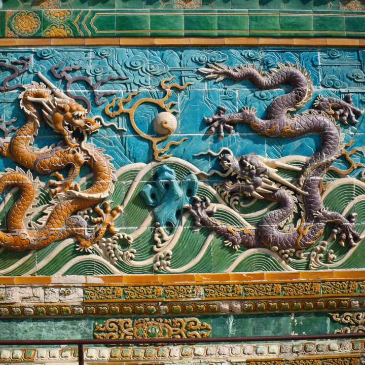 蓝绿色陶瓷墙面上饰有盘绕的龙、祥云、海浪和传统边饰浮雕。