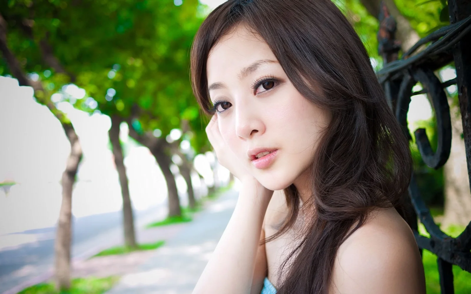 一名女性在绿树成荫的小道旁侧脸望向镜头。