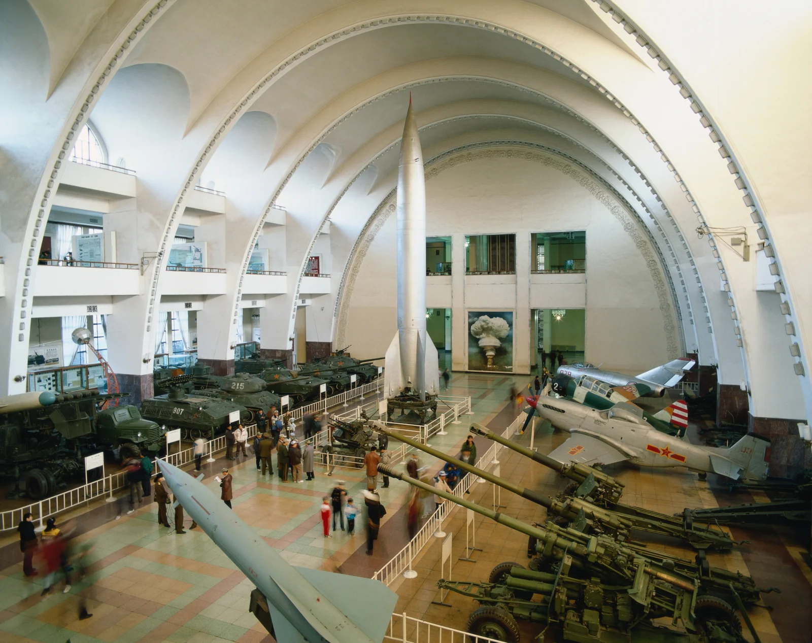 アーチ型の天井を持つ博物館のホールに、ロケット、航空機、装甲車両などの軍事展示品が並んでいる。