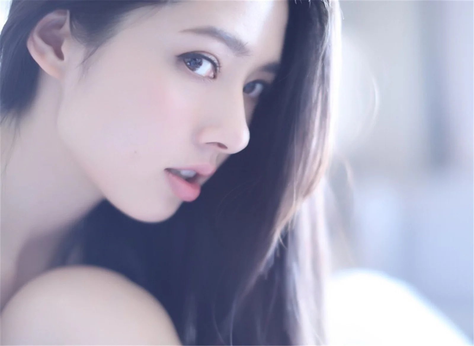 一位长发女性在柔和冷色光线下侧脸注视镜头。