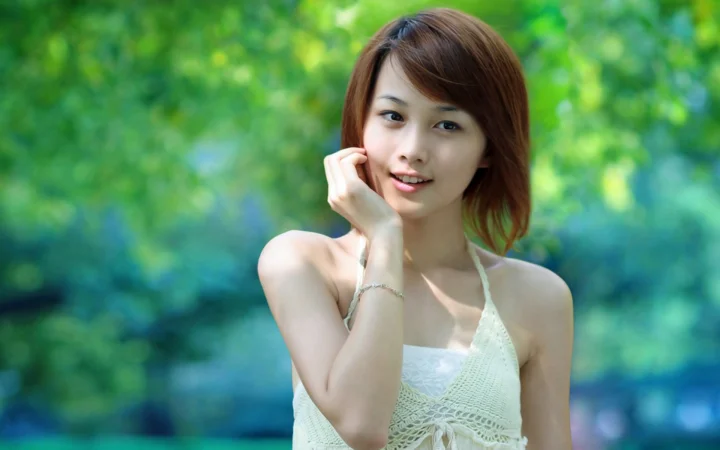 一名成年女性在绿色户外背景前微笑看向镜头。
