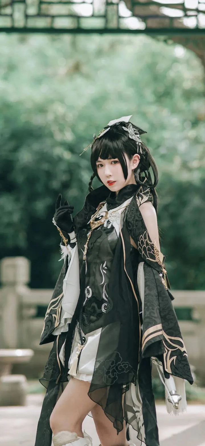 装飾的な黒い衣装を着た女性が屋外の中庭に立っています。