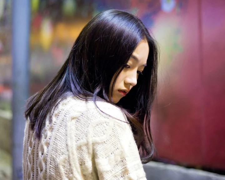 一名长发女性穿着白色针织衫侧身回望。