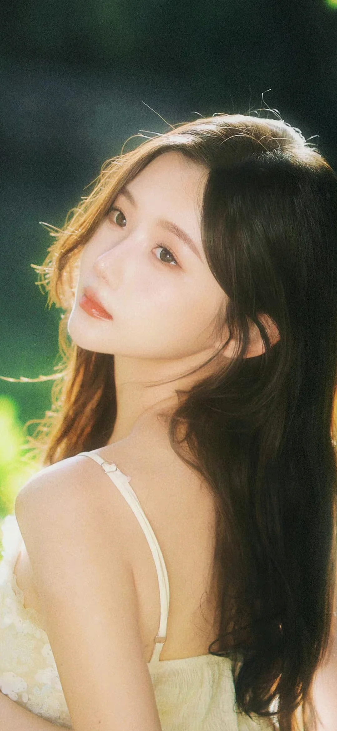 一位長髮女子在柔和的綠色背景光中回眸凝視鏡頭。