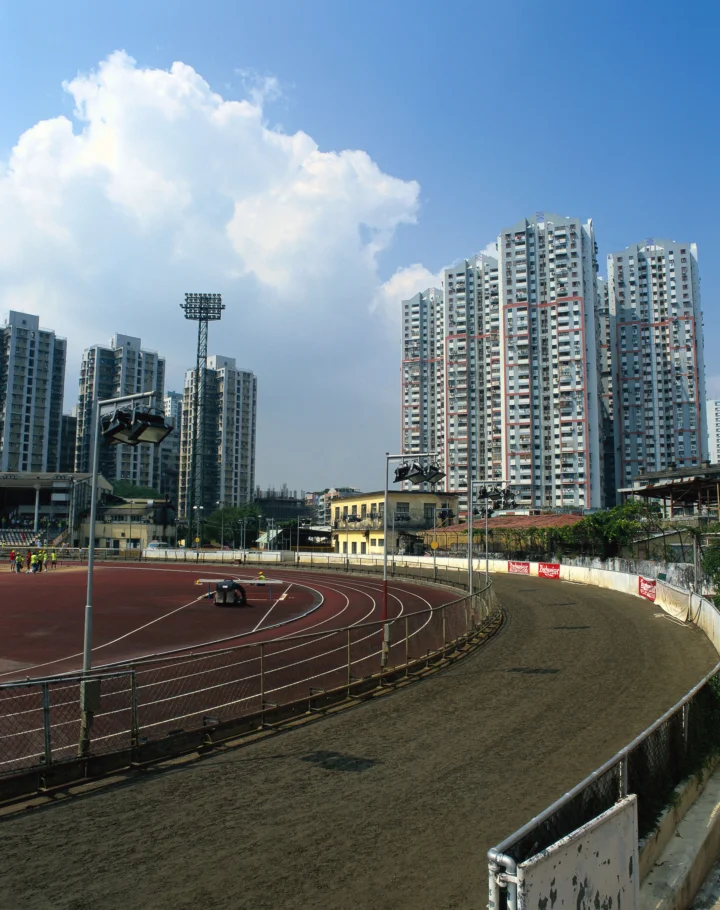 蓝天下的运动场跑道前方矗立着成排的高层住宅楼。