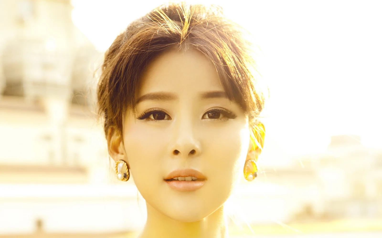 밝은 황금빛 햇살 속에서 성인 여성이 카메라를 바라보고 있다.
