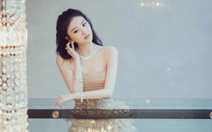 一位佩戴珠宝的成年女性坐在古琴后方，面向镜头摆姿势。