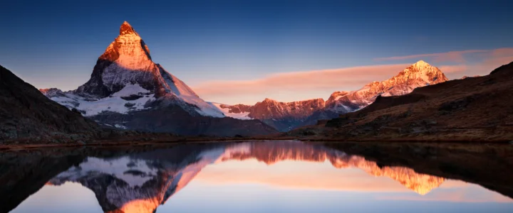 夕阳映照下的雪山与湖面倒影构成壮丽的自然风景。