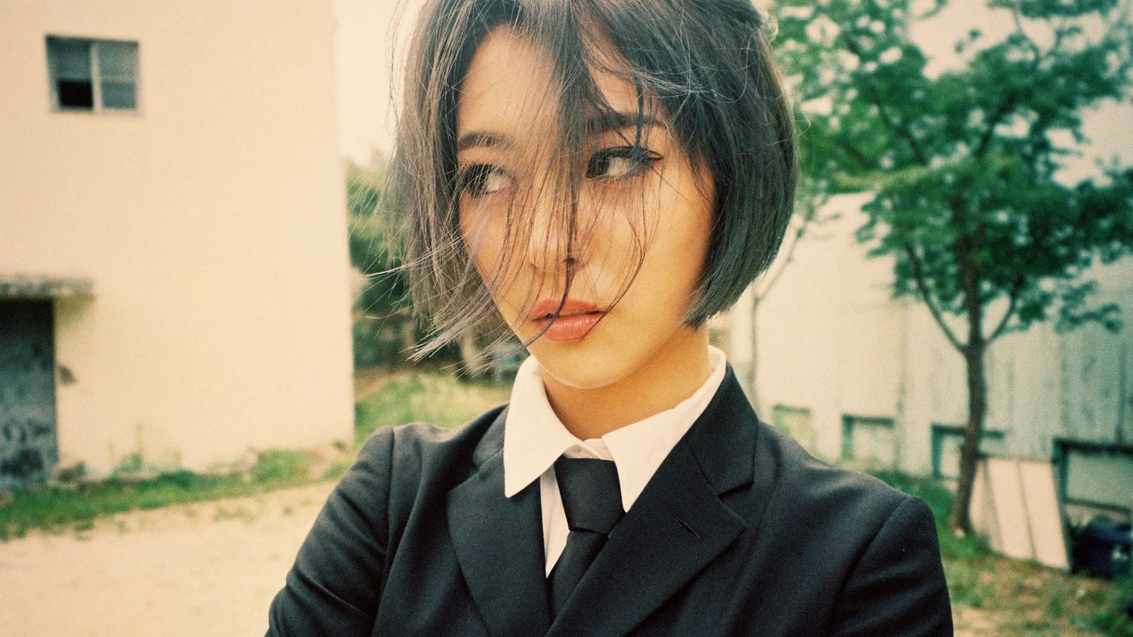 一位短发女士穿着黑色西装和白色衬衫站在户外。