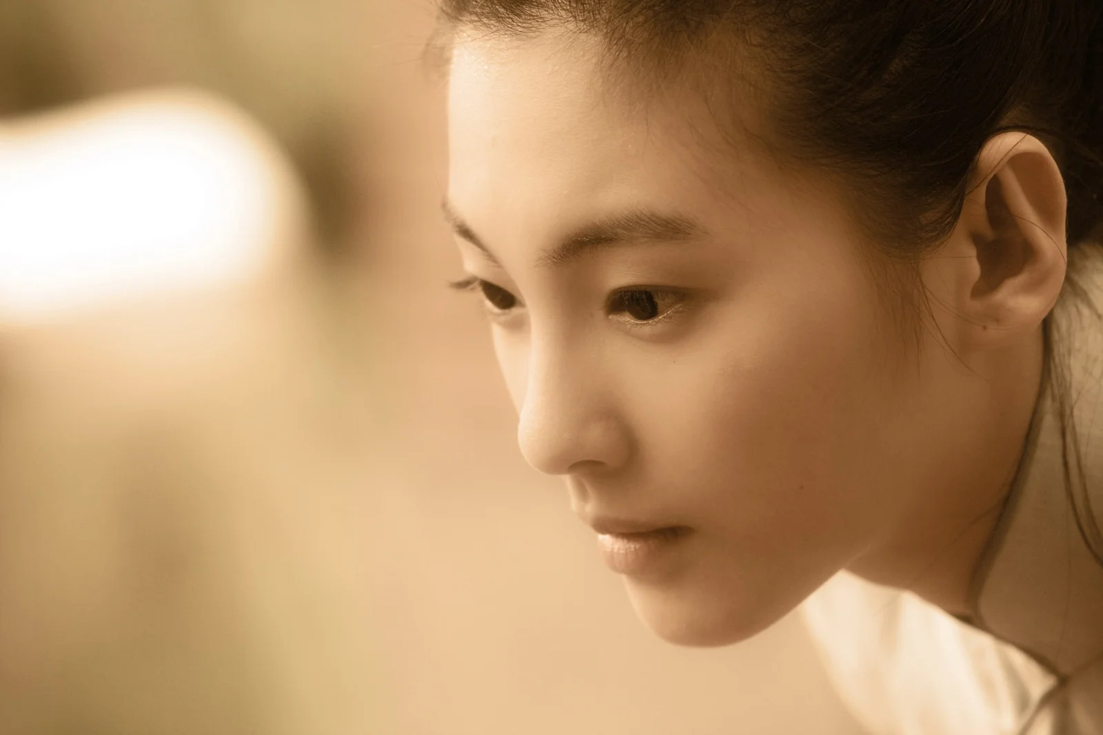 一位成年女性的面部特写沐浴在柔和的暖色光线中。