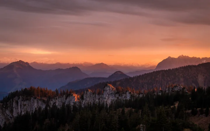 夕阳映照着远处的群山、森林与岩石山脊。