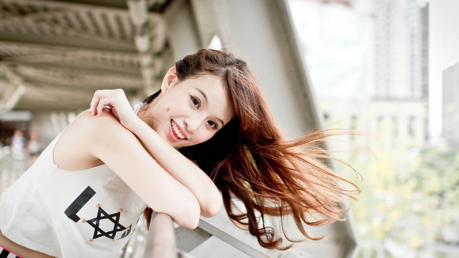 一名长发女子在桥下微笑，发丝随风飘动。