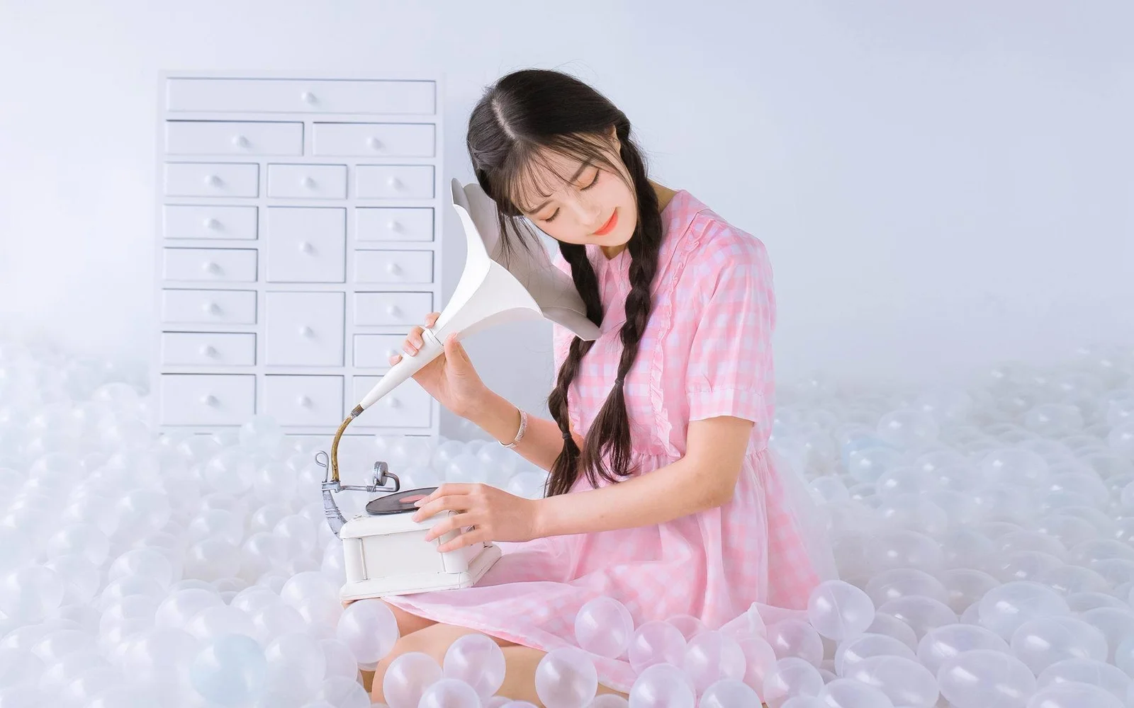 분홍색 드레스를 입은 여성이 흰색 거품 속에서 재봉틀을 작동하고 있습니다.