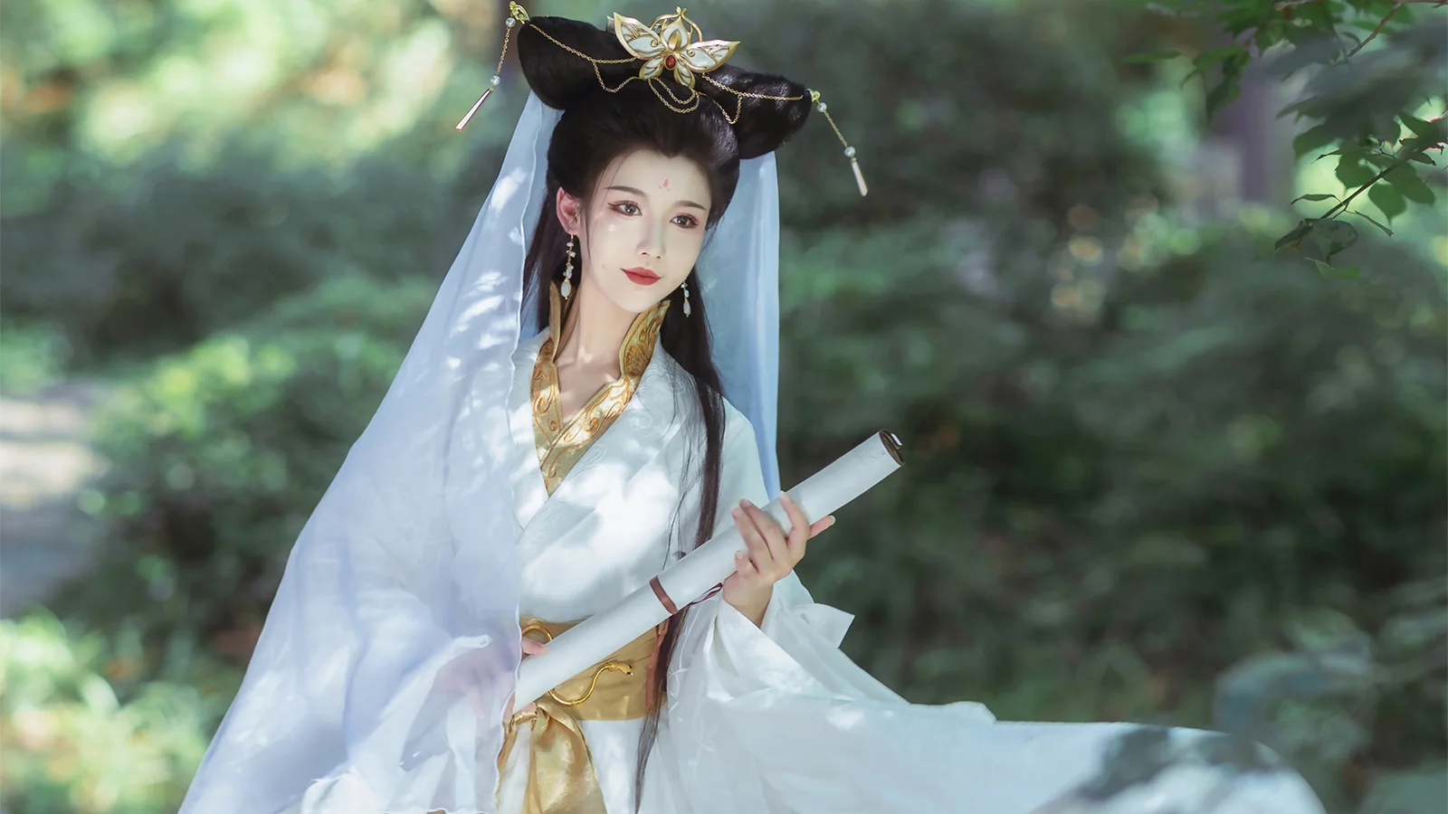 흰색 전통 의상과 장식 머리장식, 베일을 착용한 여성이 숲속에서 두루마리를 들고 있다.