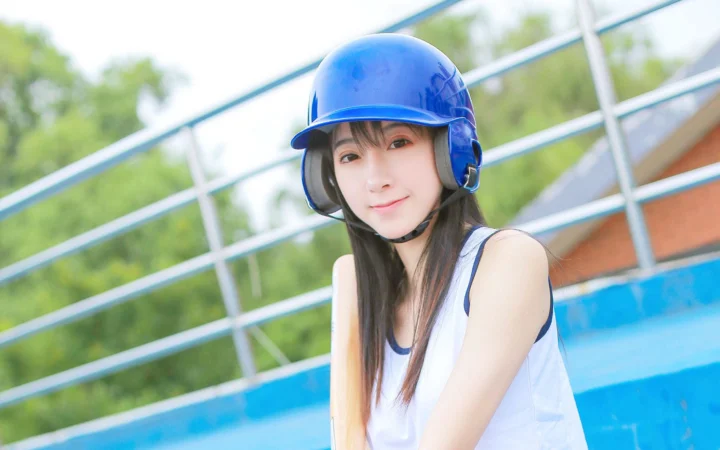 一名戴着蓝色头盔的年轻女性在户外看向镜头。