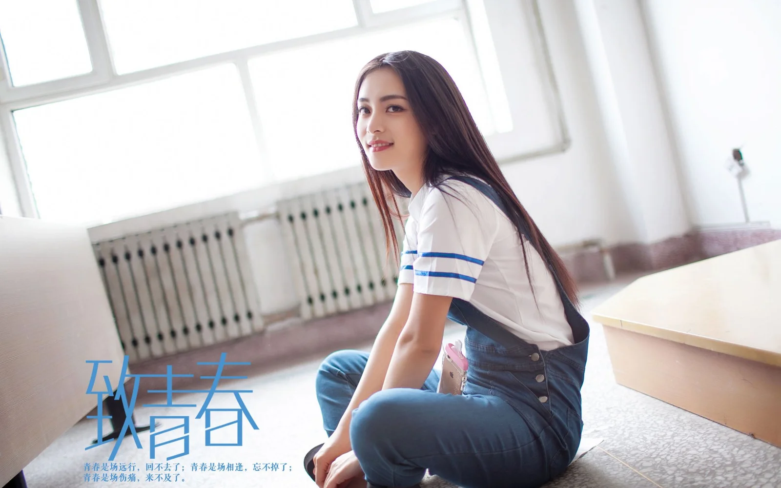 一名長髮女性穿著白色藍條紋上衣和牛仔褲，坐在明亮室內的地面上。