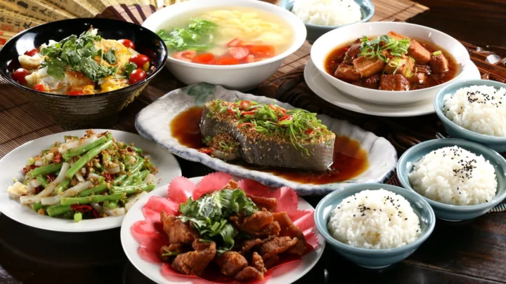 桌上摆放着鱼、肉、蔬菜、米饭和汤等多道中式菜肴。
