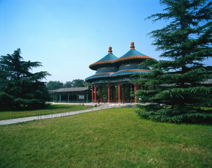 蓝天下，一座彩色屋顶的古典亭阁坐落在绿树与草坪之间。
