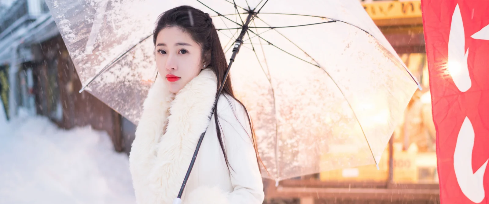 一名女子撑着透明雨伞站在雪景中。