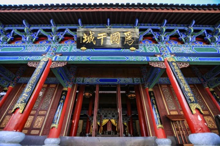 一座拥有红色立柱、蓝绿色彩绘装饰和金色牌匾的传统建筑门廊。
