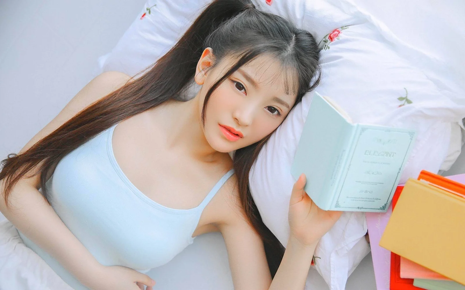 一名女性躺在床上，手里拿着一本书。