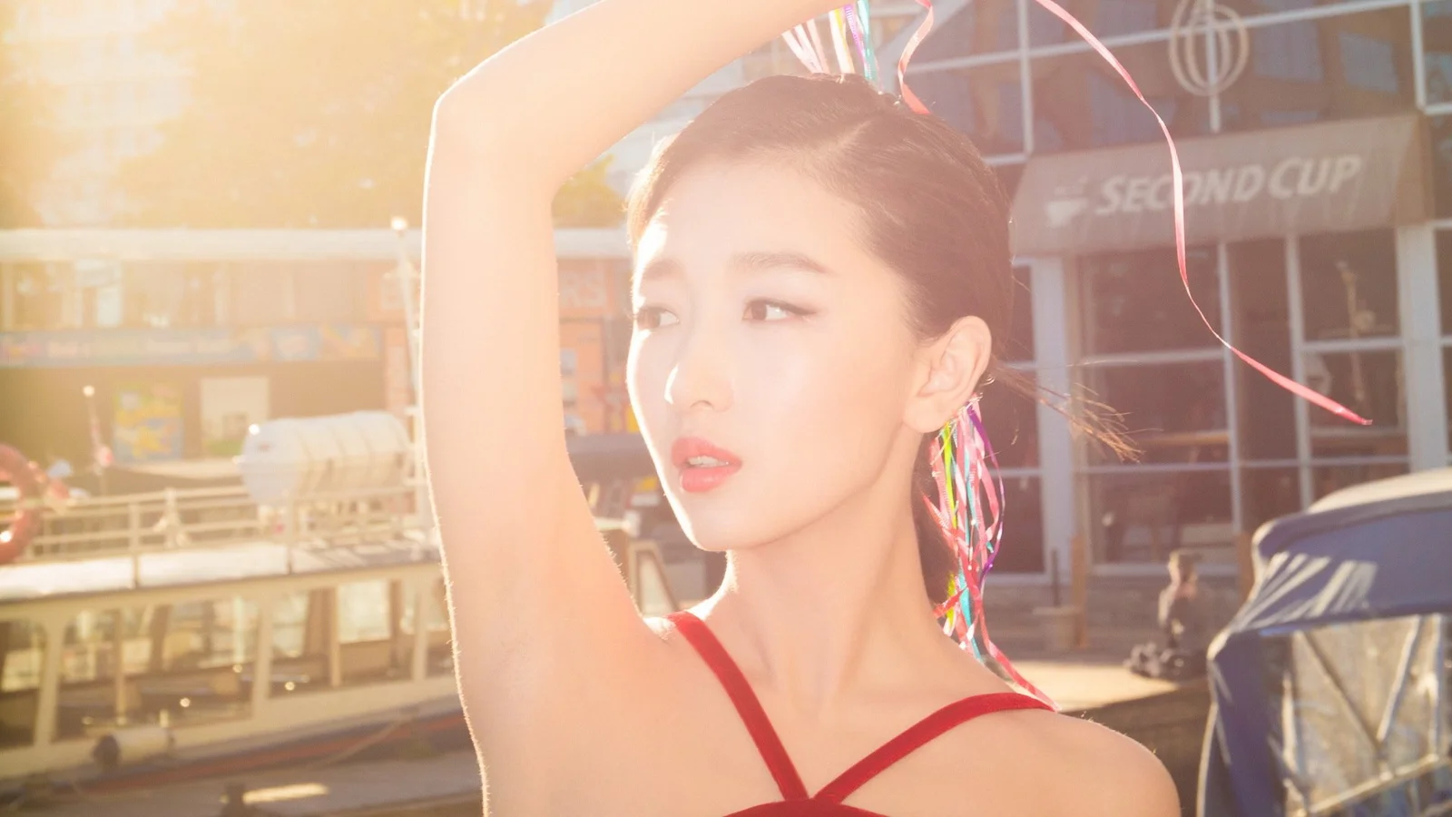 一位成年女性在阳光下抬起手臂，身后是城市街道与建筑。
