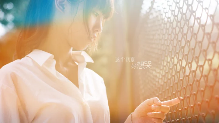 一名穿白色衬衫的女性站在带有格纹装饰的窗边，暖色阳光洒在画面上。
