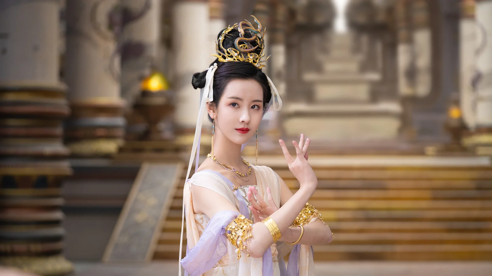 一名身着华丽传统服饰、佩戴 ornate 头饰的女子站在室内背景前摆出姿势。
