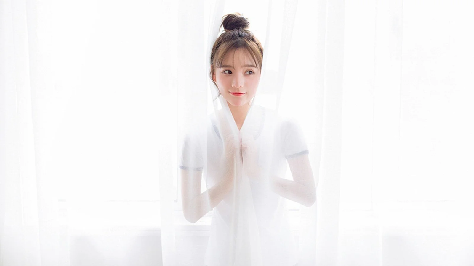 一名成年女子站在明亮的白色纱帘后。