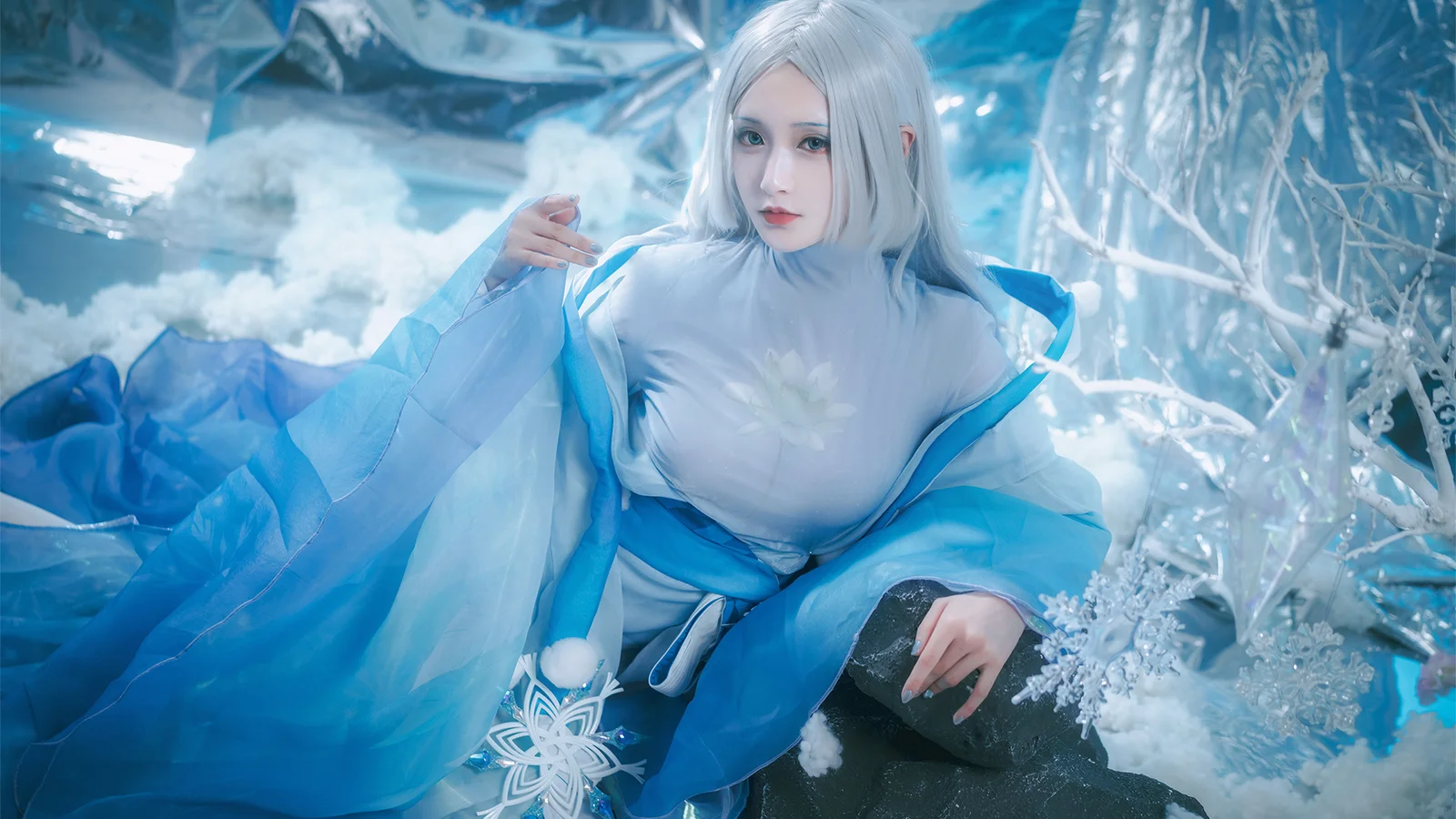 一名身穿冰藍色服裝的成年女性置身於雪景般的藍白色背景中。