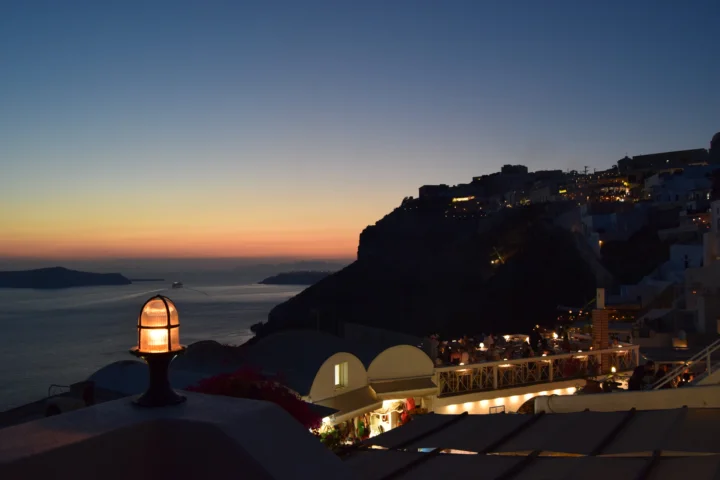 暮色中的海面、悬崖小镇与点亮的建筑共同构成宁静的海岸夜景。