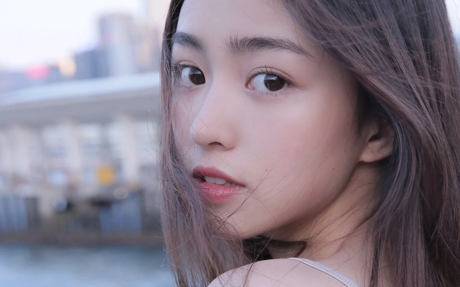 一位棕色长发女性在城市背景前回头看向镜头。