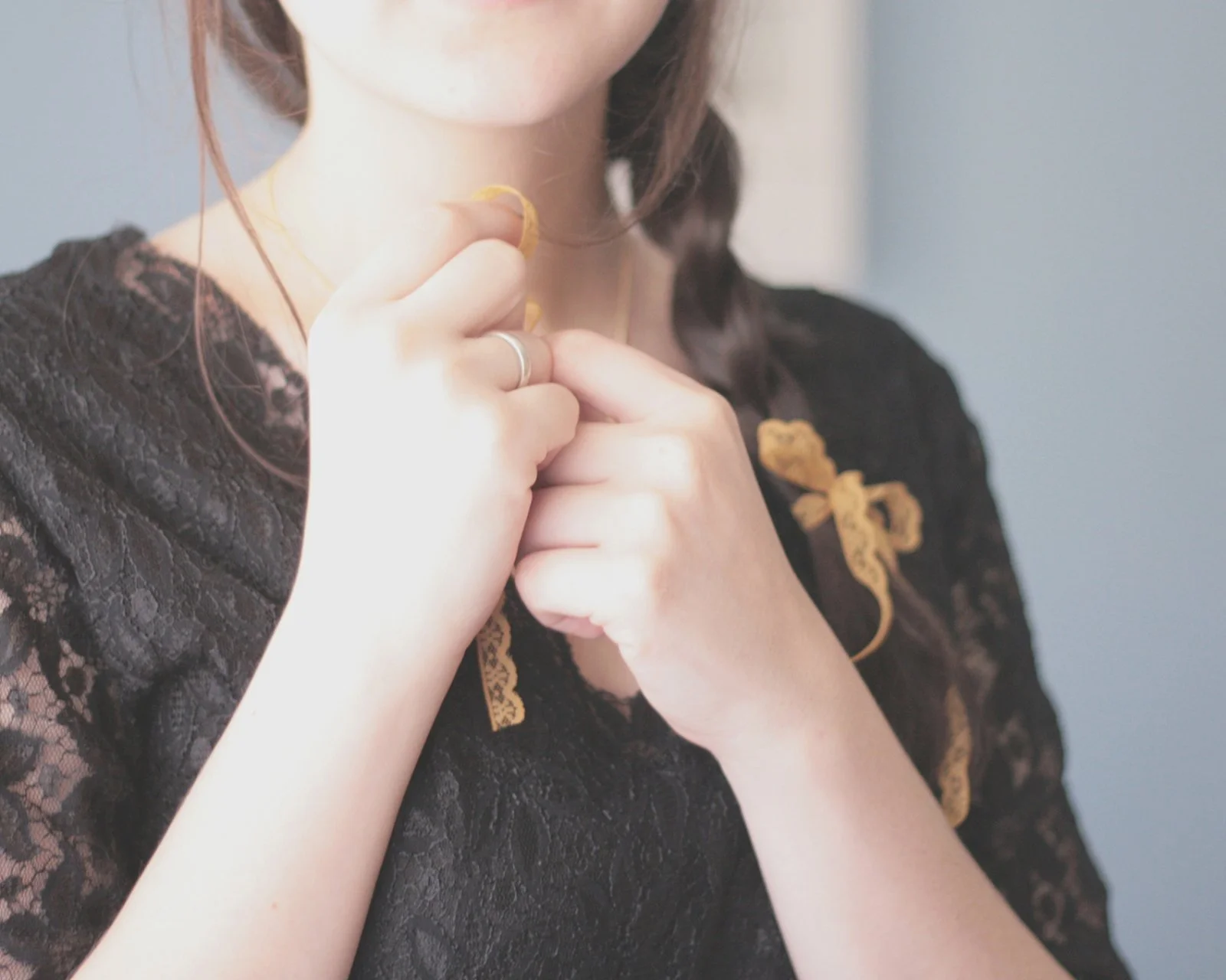 黒いレースの服を着た成人女性が、首元に手を添えているクローズアップです。