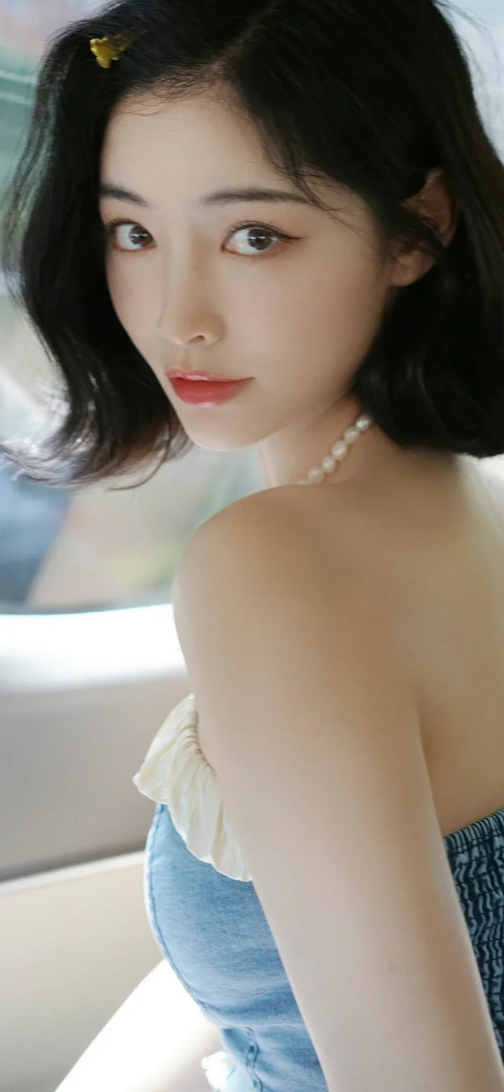 一位黑发女性佩戴珍珠项链回眸看向镜头。