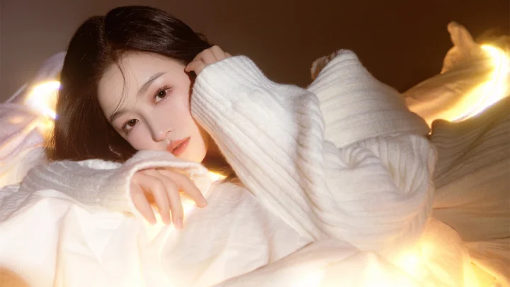 一名成年女性穿着白色针织衫躺在柔和的暖光中。
