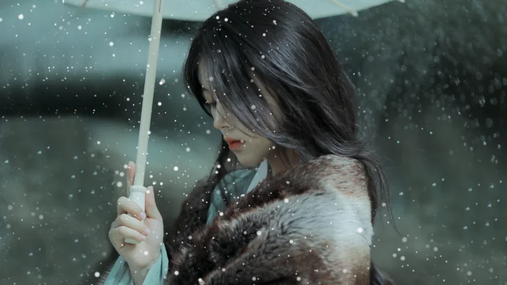 一名女子在雨中撑着伞，黑发和深色外套被飞溅的雨滴环绕。