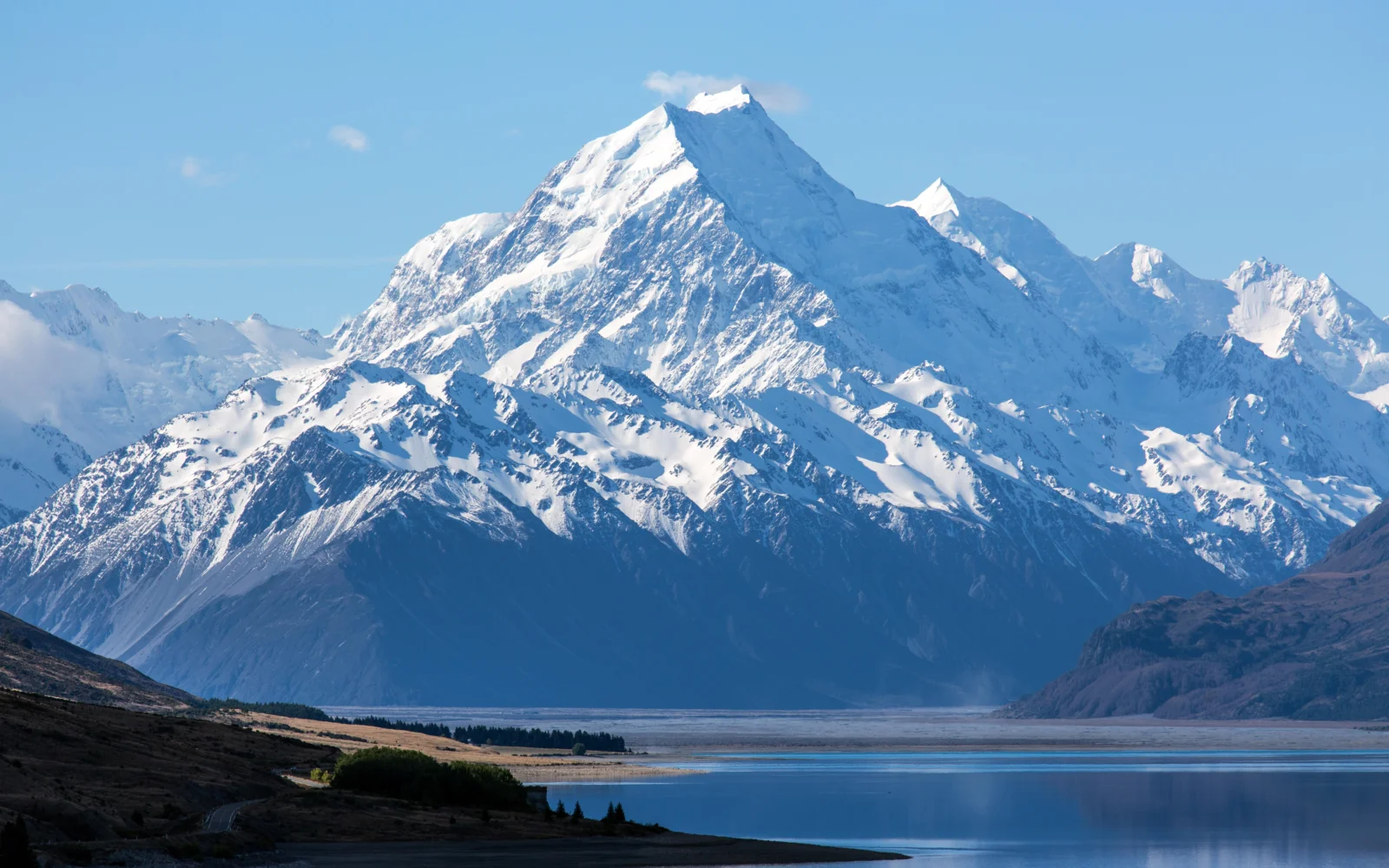 雄偉的積雪山峰矗立在寧靜的湖泊與藍天下。
