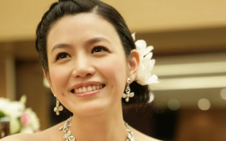 一位佩戴花朵发饰和耳饰的女性在室内微笑肖像。