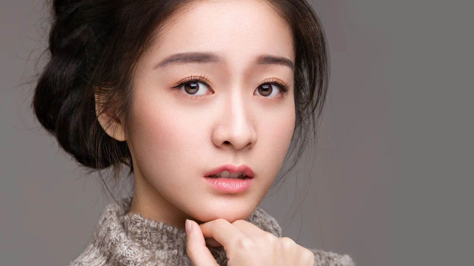 一名成年女性在灰色背景前的近距离肖像。