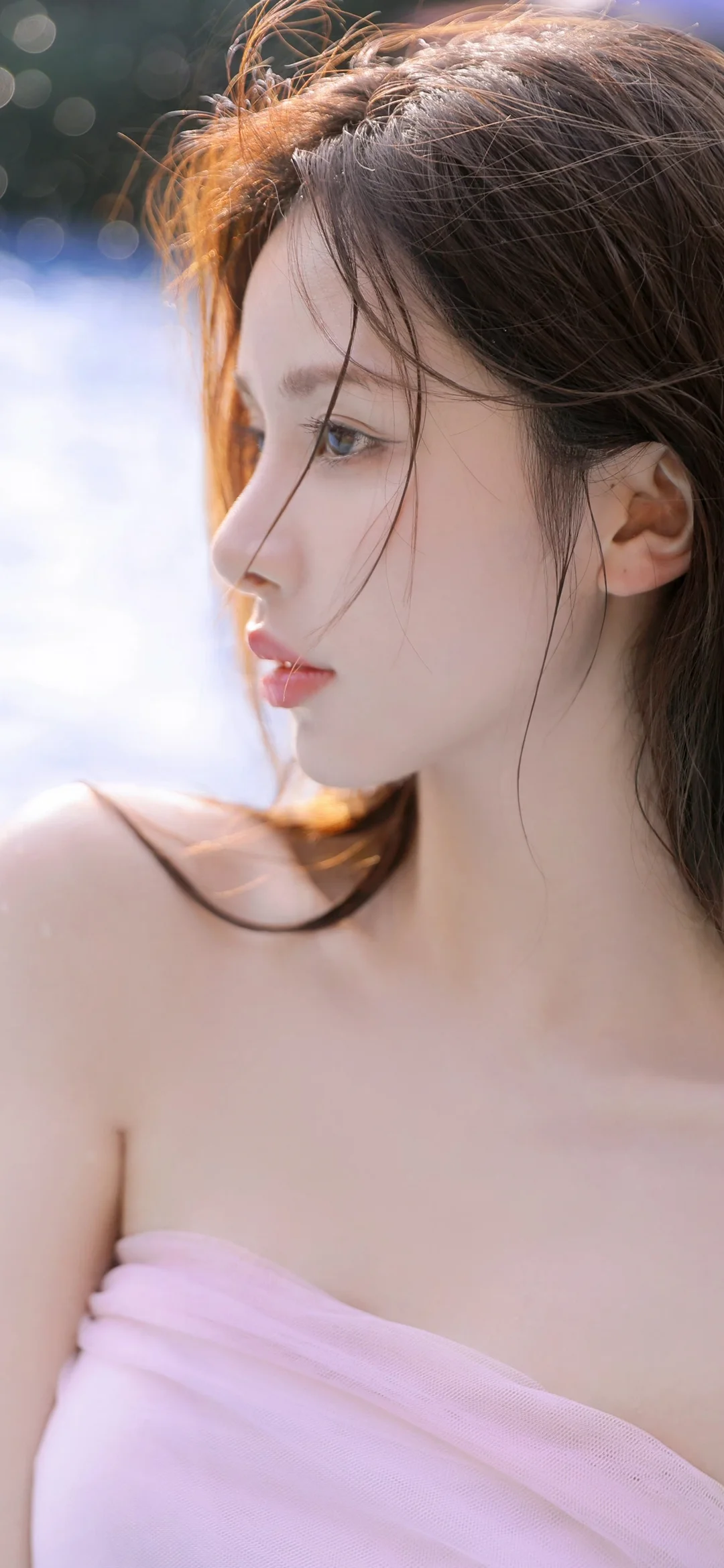 一位成年女性在柔和光线下的侧脸近照，发丝随风轻拂，肩部披着淡紫色布料。