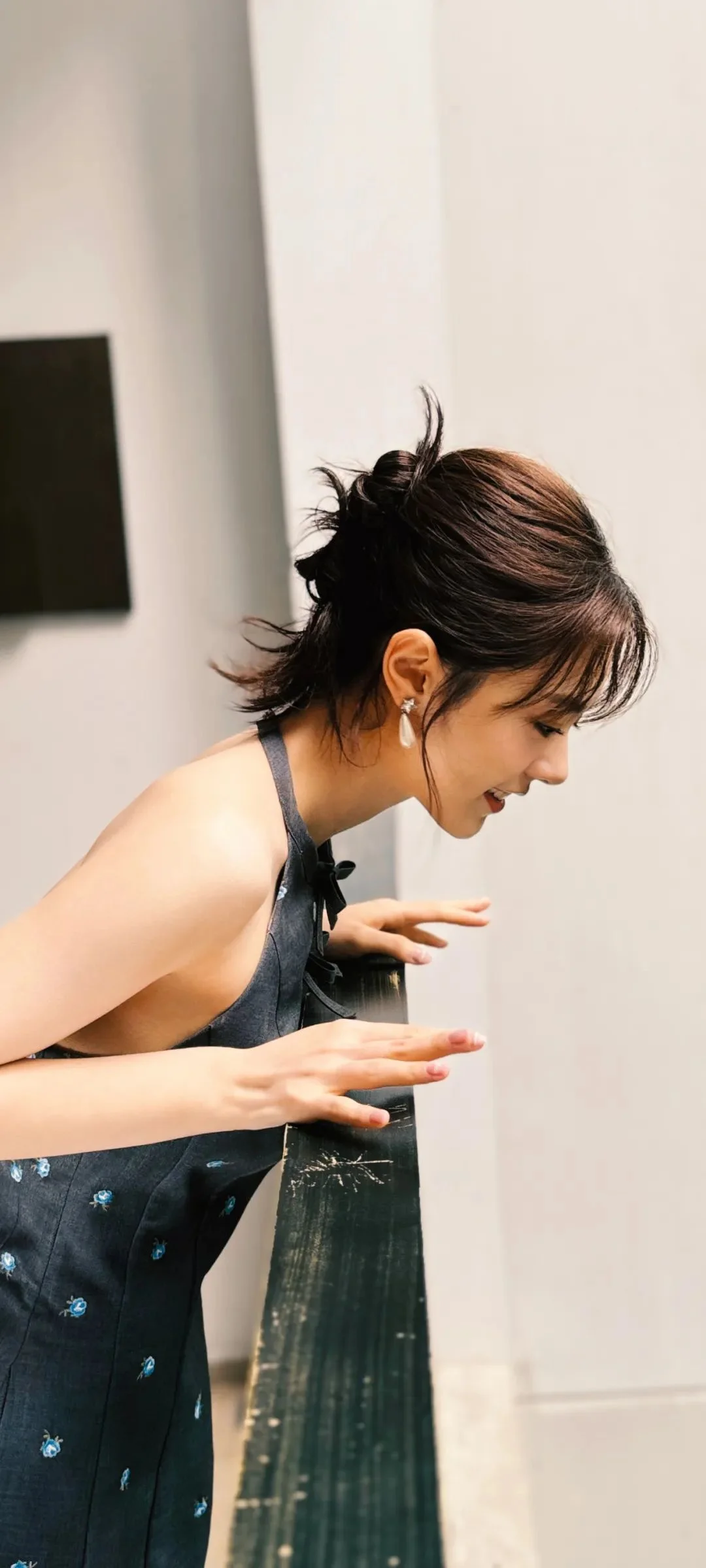 검은색 원피스를 입은 성인 여성이 실내에서 몸을 숙인 채 옆모습을 보이고 있다.