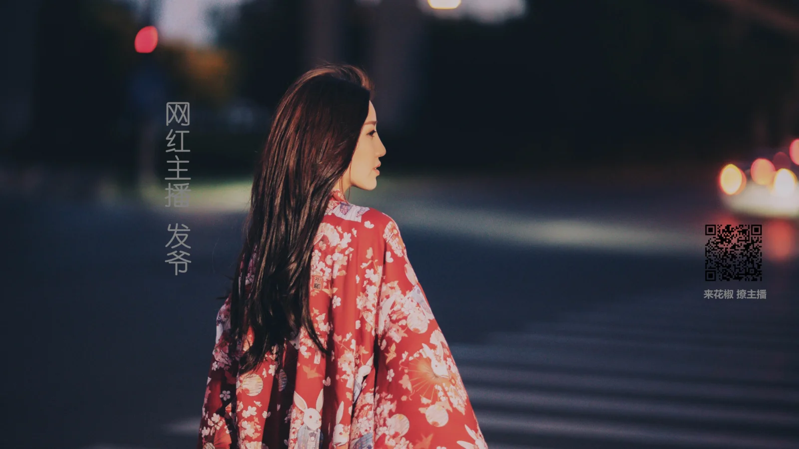一名身穿紅色花紋服裝的成年女子在夜晚街邊側身而立。