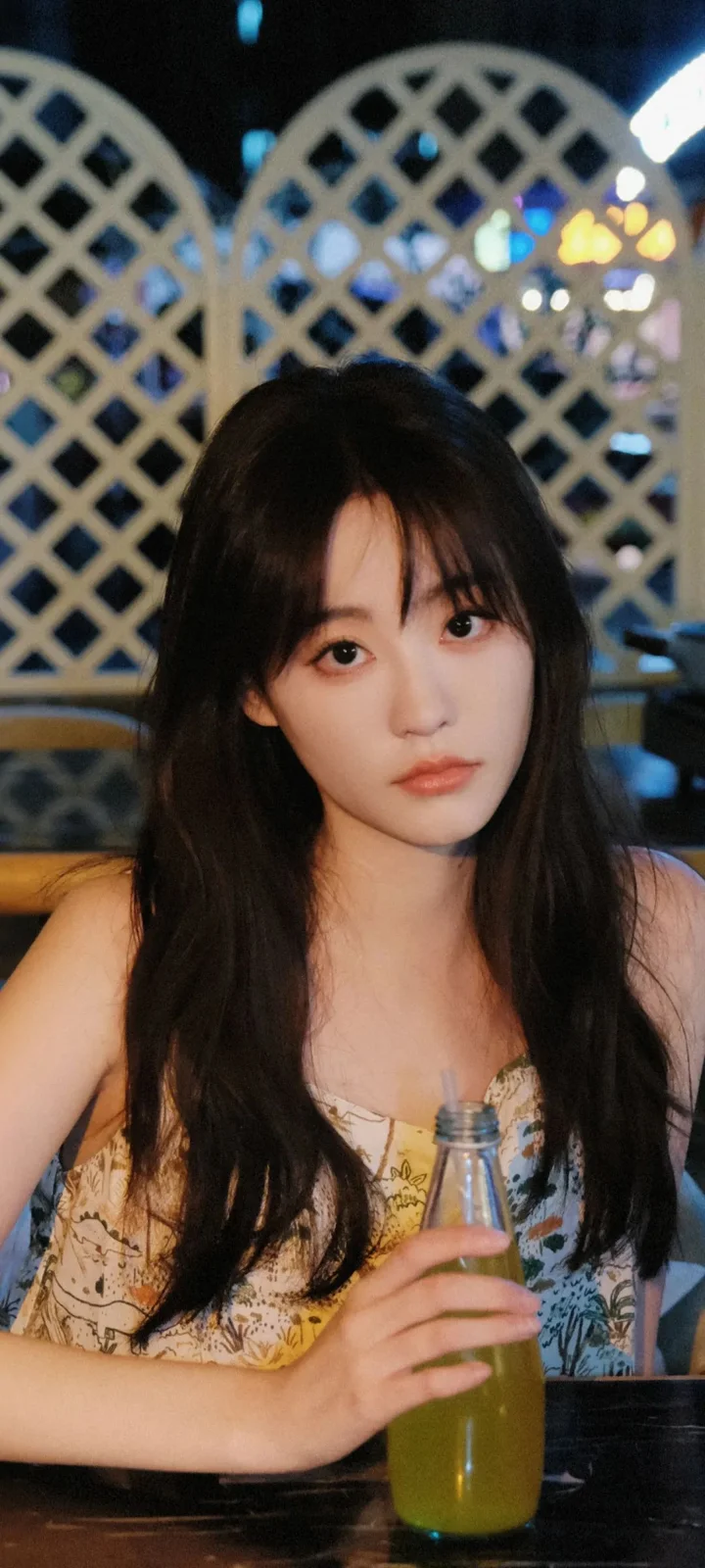 一名長髮女性在室內手持飲料瓶面向鏡頭。