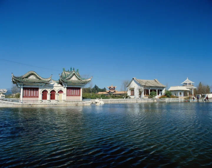 蓝天下，湖水前坐落着一组传统中式古建筑与亭台楼阁。