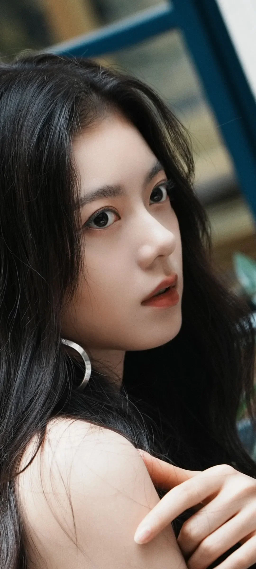 一位黑发女性的近距离侧脸肖像，背景可见模糊的室内元素。