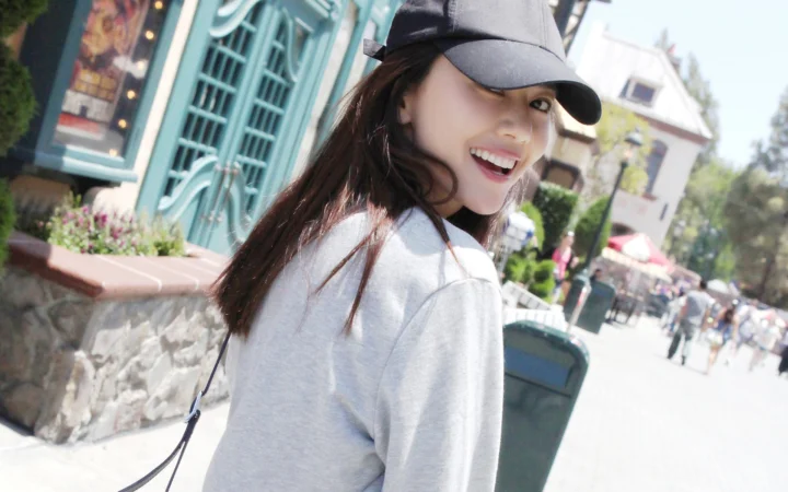 一名戴着黑色棒球帽的女子在户外街道上回头微笑。
